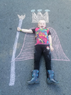 Bachgen yn gorwedd ar lun gwisg mewn sialc