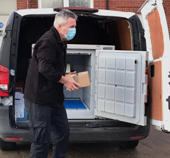 Gwynfor gyda'r brechlyn cyntaf yn cyrraedd Ysbyty Maelor